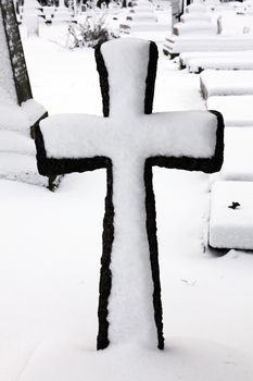 Old snow covered granite tombstone stone cross found in an old graveyard in a Christmas winter season stock photo