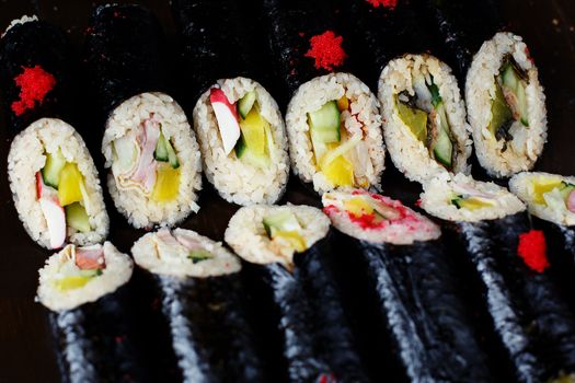 set of Korean rolls in a black shell on a white plate closeup photo