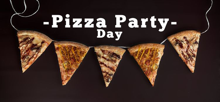 sliced slices of pizza on a sulphurous background hung on a rope with the inscription Pizza party day top view photo