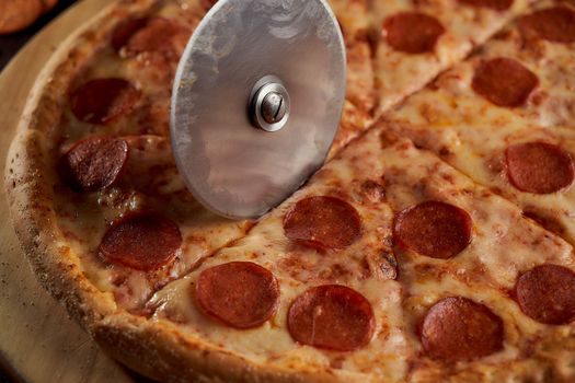 A special pizza knife cuts the pepperoni into pieces. closeup photo