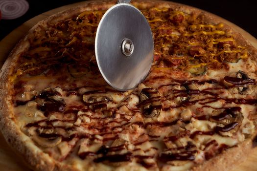 A special pizza knife cuts it into pieces. closeup photo