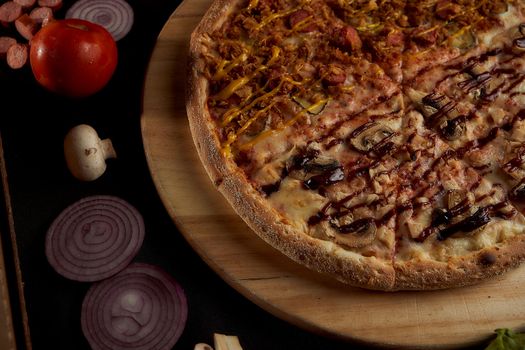 The finished pizza rests on a wooden tray with ingredients. black closeup photo