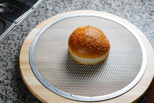 Burger bun rests on iron grill for pizza closeup photo