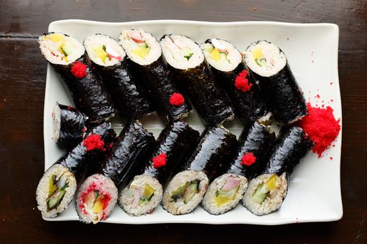 set of Korean rolls in a black shell on a white plate top view photo