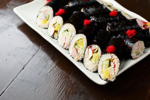 set of Korean rolls in a black shell on a white plate closeup photo