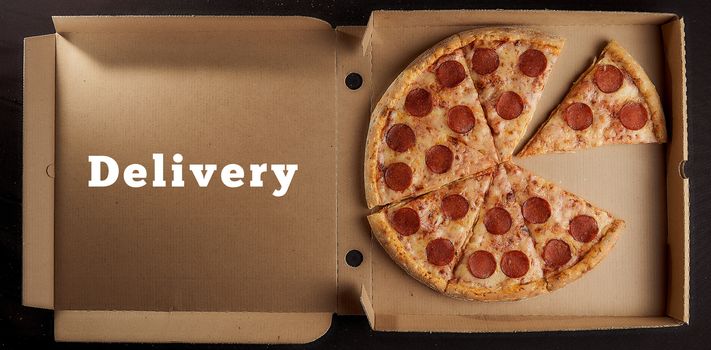Pepperoni pizza lies in a cardboard box with the inscription Delivery Beautiful concept background
