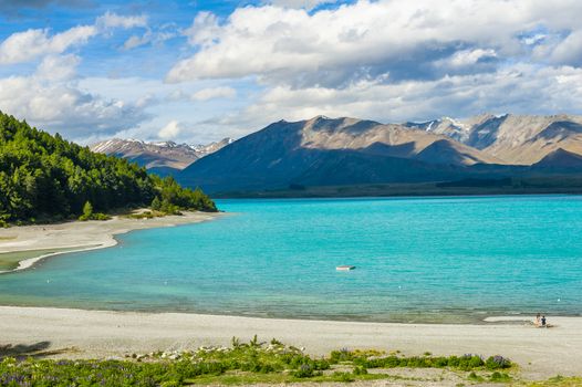 Beautiful incredibly blue lake Tekapo with mountains, Southern Alps, on the other side. New Zealand