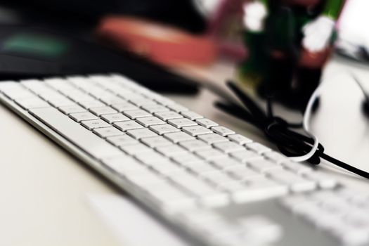 a modern gray computer keyboard with white keys on an office table. Shallow depth of field. Occupation and office work