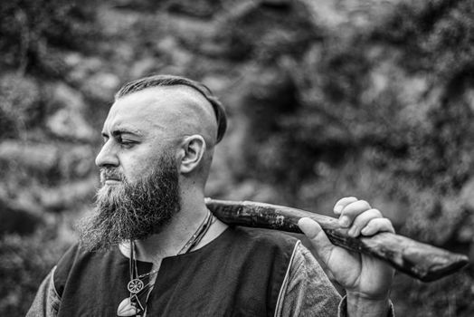 Viking portrait with thick beard, black and white image of historical re-enactment among medieval ruins