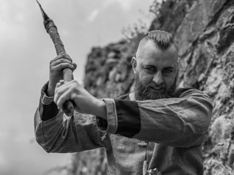 Viking warrior with thick beard brandishes an ax, image of historical re-enactment in black and white