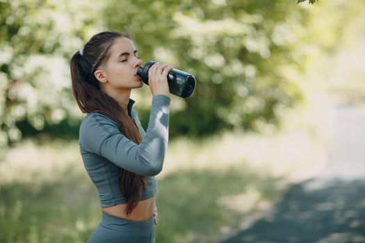 Tired runner woman jogger drinking bottled water after jogging