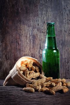 Peanuts and greed beer bottle in wood background
