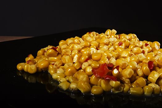 Tinned corn with pepper on a black plate