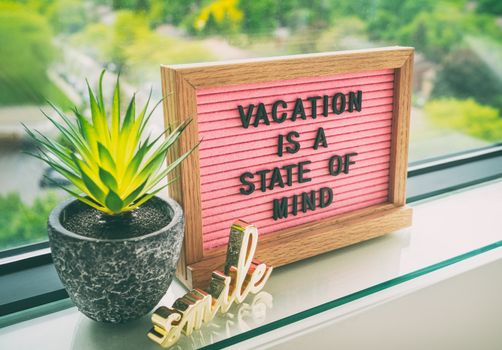 Vacation is a state of mind positive inspirational quote text on message board for summer holiday travel during COVID-19 coronavirus. Staycation pink felt board text for staying home.