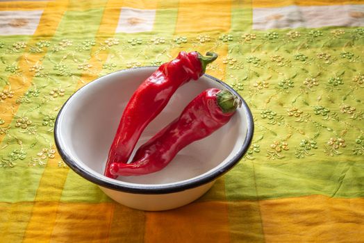 Hot red chili peppers in an enamel bowl, put on an orange and green napkin