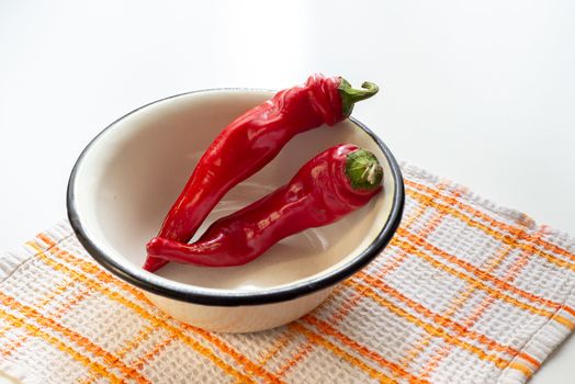 Hot red chili peppers in an enamel bowl, put on an orange and white napkin