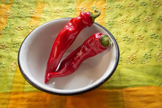 Hot red chili peppers in an enamel bowl, put on an orange and green napkin