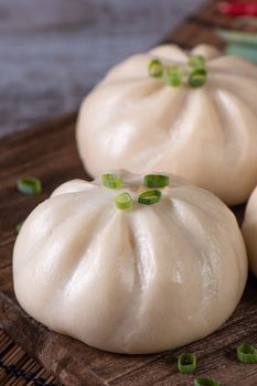 Delicious baozi, Chinese steamed meat bun is ready to eat on serving plate and steamer, close up, copy space product design concept.