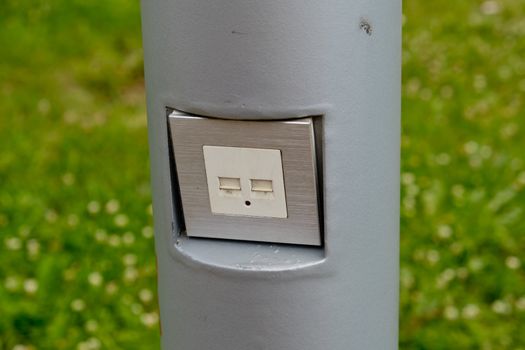 USB socket for charging mobile phones on a pole in the park.