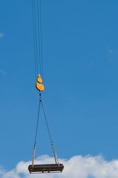 The crane lifts a heavy load on a hook.