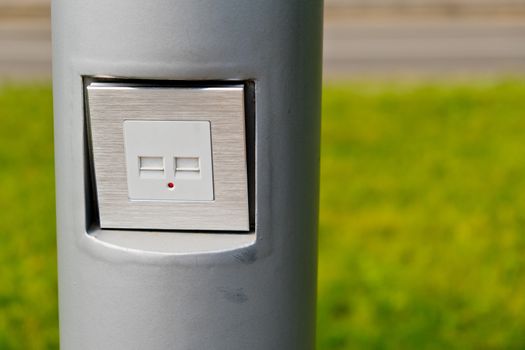 USB socket for charging mobile phones on a pole in the park.