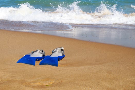 flippers on the sand against the background of the sea, copy space