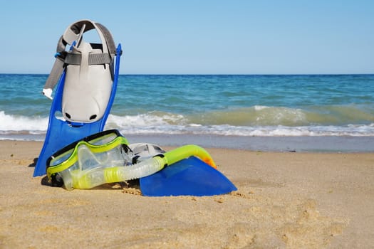 flippers and mask for swimming on the sand against the background of the sea and clear sky, copy space