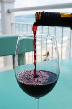 wine is poured into a glass against the background of the sea