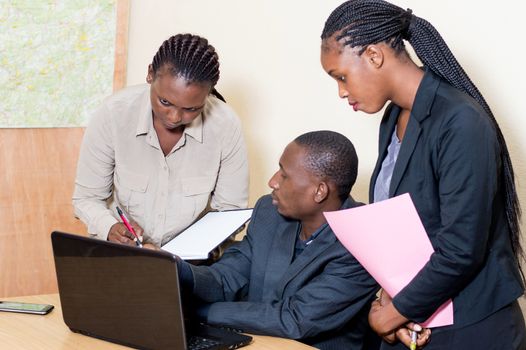 Three business partners working on a laptop in the office.