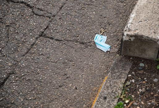 The coronavirus pandemic did not change bad habits: a disposable blue surgical mask was irresponsibly thrown on the ground along the way