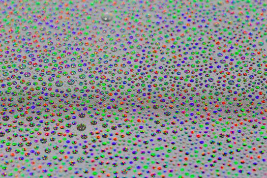 many small water drops on the surface of cellphone hydriphobic coated glass screen, close-up with selective focus and visible subpixel rgb triads