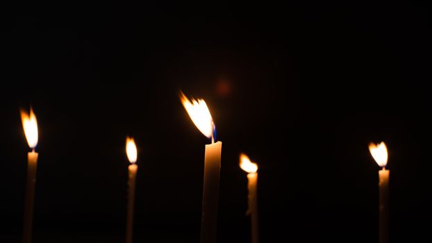 Close-up shots of yellow candles and lights on a black background with bokeh lights