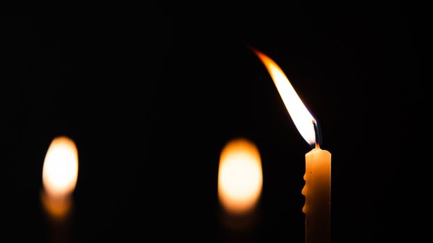 Close-up shots of yellow candles and lights on a black background with bokeh lights