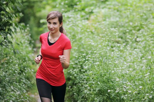 Young fitness woman running in the morning forest trail. Motivation healthy fit living. Running shoe of the person running in nature with beautiful sunlight. Woman warming up before running