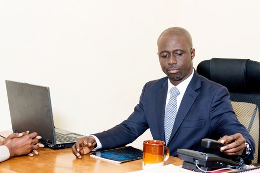 Young businessman with laptop, coffee and a phone at the office.