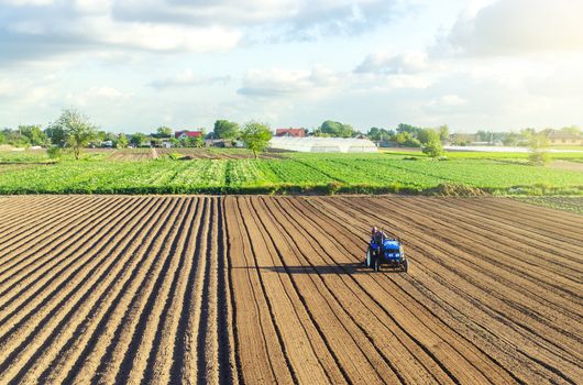A tractor rides on a farm field. Farmer on a tractor with milling machine loosens, grinds and mixes soil. Loosening the surface, cultivating the land for further planting. Farming and agriculture.