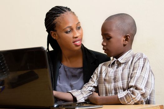 Smiling young woman learns computer skills from child with kindness.