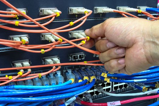 Technician connect fiber cable network to switch port in server room , Concept internet network management

