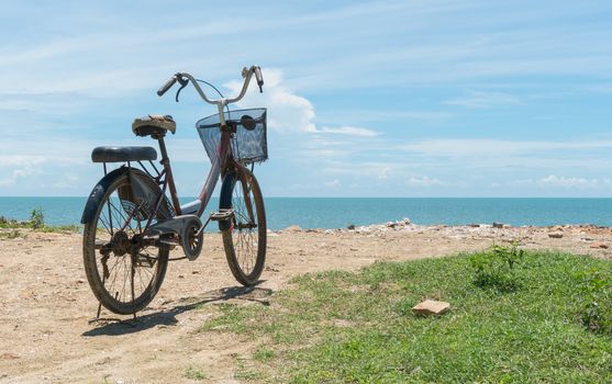 Red bicycle on beach and blue sky and sea or brine. Bicycle on rock or stone mound or pile. Landscape summer concept in relaxation mood for 
design