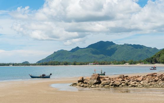Blue fishing boat on beach and green hill and sea and reef or rock. Fisherman boat or fishing boat for summer concept at Prachuap Khiri Khan 
Thailand