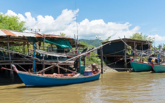 Fishing village and fishing boat at Khao Dang village. Old home and fishing boat and blue sky and cloud and water and green tree. Landscape or 
scenery summer concept for boat trip