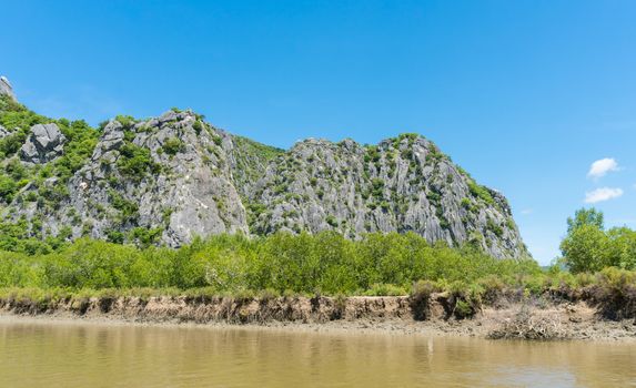 Stone or rock mountain or hill with green tree and blue sky and water and cloud at Khao Dang canal Prachuap Khiri Khan Thailand. Landscape or scenery summer concept for boat trip