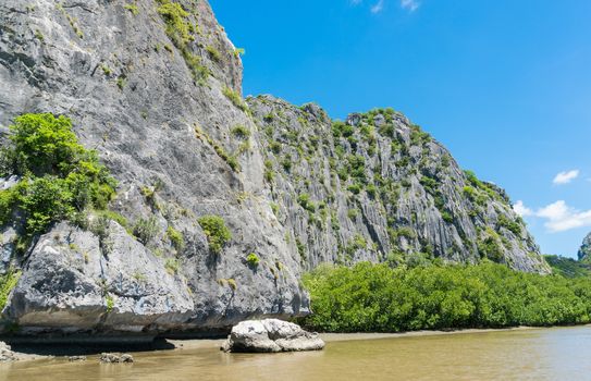 Stone or rock mountain or hill with green tree and blue sky and water and cloud at Khao Dang canal Prachuap Khiri Khan Thailand. Landscape or scenery summer concept for boat trip