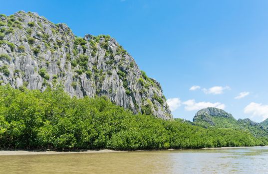 Stone or rock mountain or hill with green tree and blue sky and water and cloud at Khao Dang canal Prachuap Khiri Khan Thailand. Landscape or scenery summer concept for boat trip