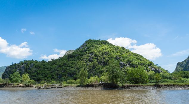 Stone or rock mountain or hill with green tree and blue sky and water and cloud at Khao Dang canal Prachuap Khiri Khan Thailand. Landscape or scenery summer concept for boat trip