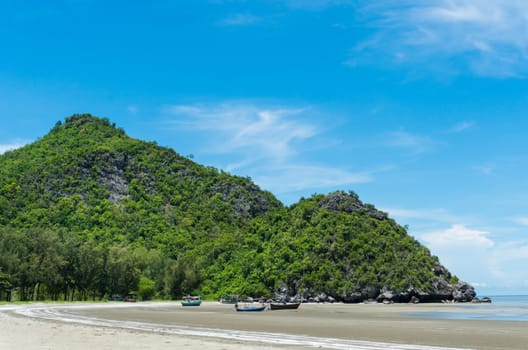 Rock or stone mountain or hill and blue sky and fishing boat at Sam Phraya beach Prachuap Khiri Khan Thailand. Landscape or scenery in 
natural for summer concept