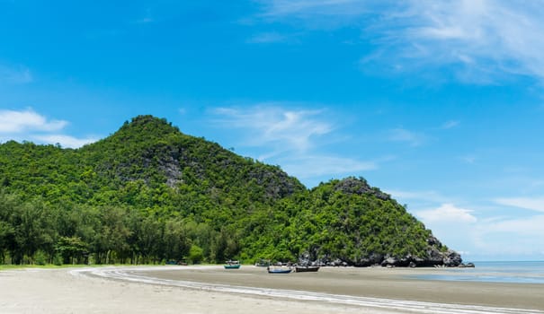 Rock or stone mountain or hill and blue sky and fishing boat at Sam Phraya beach Prachuap Khiri Khan Thailand. Landscape or scenery in 
natural for summer concept