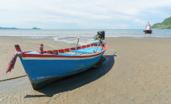 Blue fishing boat or fisherman boat or ship on Sam Roi Yod bech Prachuap Khiri Khan Thailand with blue sky and cloud and blue sea and 
mountain or hill. Landscape or scenery for summer season concept