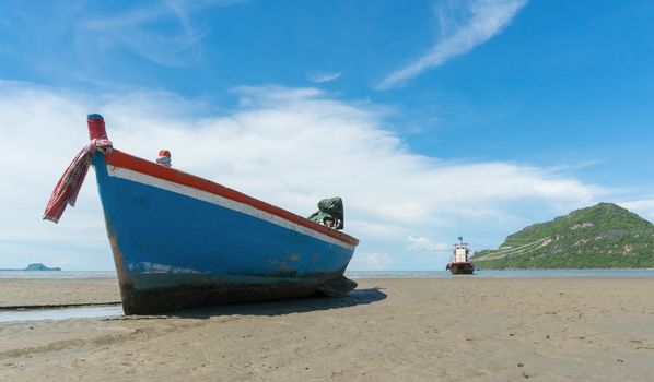 Blue fishing boat or fisherman boat or ship on Sam Roi Yod bech Prachuap Khiri Khan Thailand with blue sky and cloud and blue sea and 
mountain or hill. Landscape or scenery for summer season concept