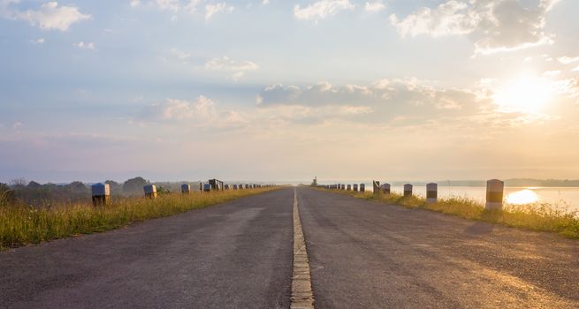 The Road on Dam or Sluice with Sunshine Blue Sky Water and Cloud Center Frame. Road on dam or sluice and natural landscape cloud blue sky sunshine fog and water